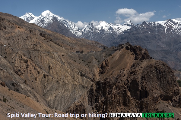 Rugged Spiti Valley ridges and snow peaks, framing the choice between a high‑village trek and a road trip